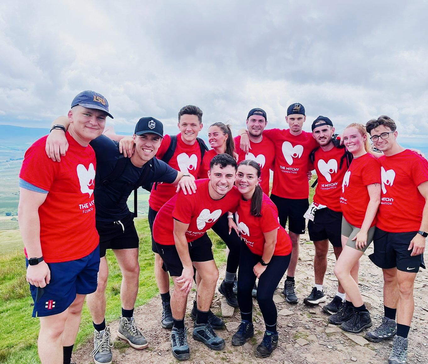 A group of Mitchy Foundation supporters smiling together on the Yorkshire hillside during the three peaks challenge.